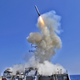 A U.S. Navy guided-missile destroyer, USS Barry (DDG 52), launching Raytheon-manufactured Tomahawk missiles during the opening phases of the international military intervention that ended in the overthrow of the Libyan government in 2011.
